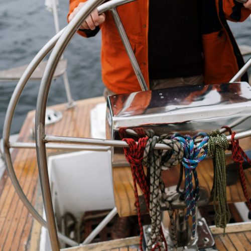 Close-up of a sailor holding the helm of a sailboat, navigating the open sea.